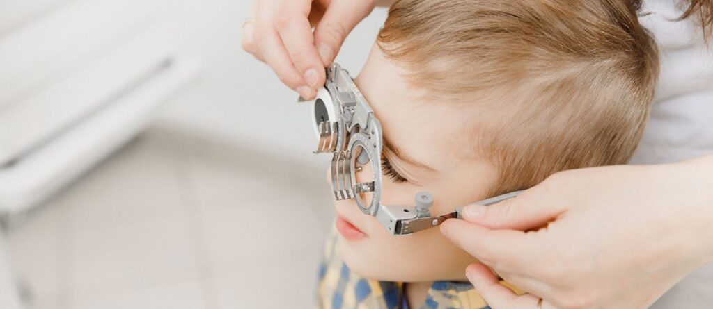 Ein Kind erhält eine Augenuntersuchung mit einer Testbrille beim Optiker
